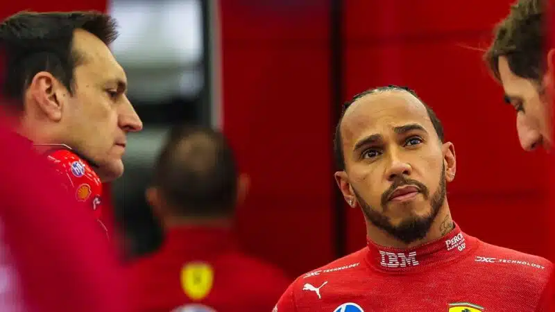 Lewis Hamilton a Ferrari vörös csapatpólójában beszélget a boxutcában.